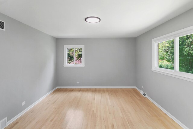 spare room featuring visible vents, light wood finished floors, and baseboards