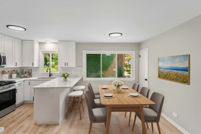kitchen with appliances with stainless steel finishes, tasteful backsplash, a sink, a peninsula, and a breakfast bar