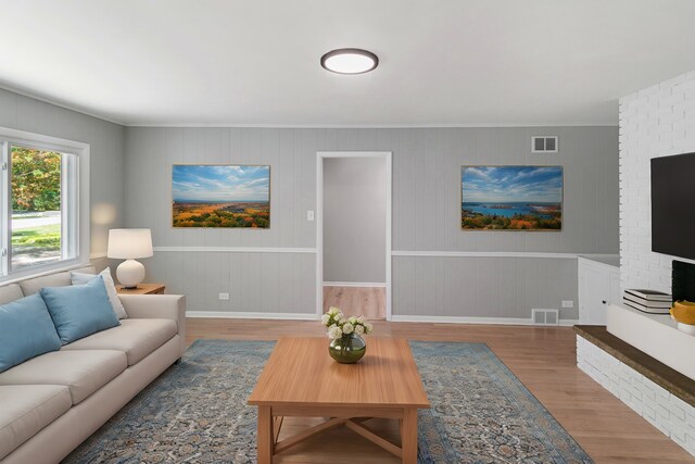 living room with crown molding, baseboards, visible vents, and wood finished floors