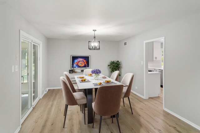 dining room with baseboards, a chandelier, visible vents, and light wood-type flooring