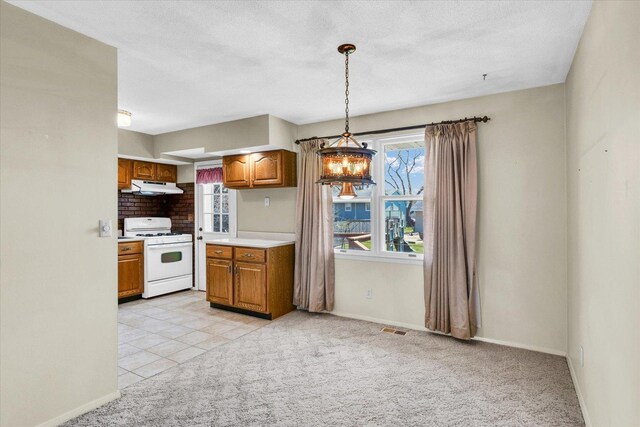 1618 Carolina Dr, Rantoul, IL 61866 - kitchen with visible vents, under cabinet range hood, brown cabinets, white gas range oven, and light carpet