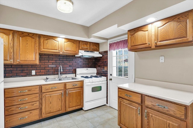 1618 Carolina Dr, Rantoul, IL 61866 - kitchen with brown cabinets, under cabinet range hood, a sink, and white gas range oven