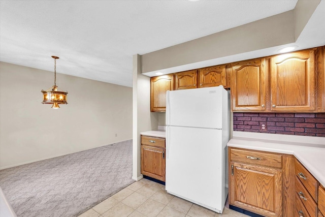 1618 Carolina Dr, Rantoul, IL 61866 - kitchen with pendant lighting, freestanding refrigerator, light colored carpet, light countertops, and brown cabinets