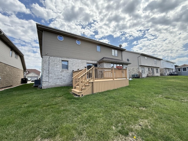 rear view of house featuring brick siding, a wooden deck, a yard, and central AC