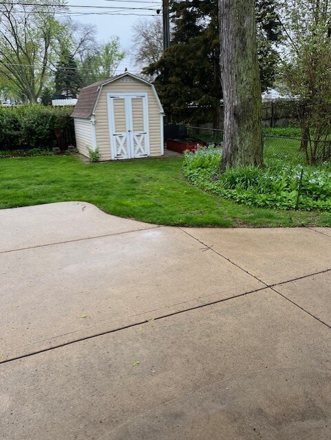 view of yard with a patio, a shed, an outbuilding, and fence