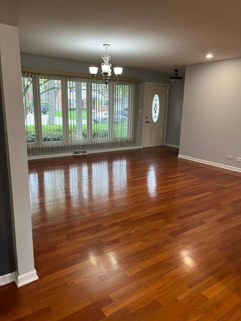 spare room featuring baseboards, recessed lighting, wood finished floors, and a chandelier