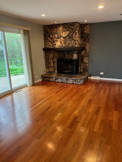 unfurnished living room featuring visible vents, baseboards, wood finished floors, and a fireplace