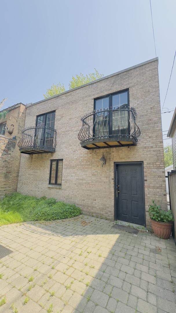1745 W Cornelia Ave, Chicago, IL 60657 - view of front of home with a balcony, brick siding, and a patio area