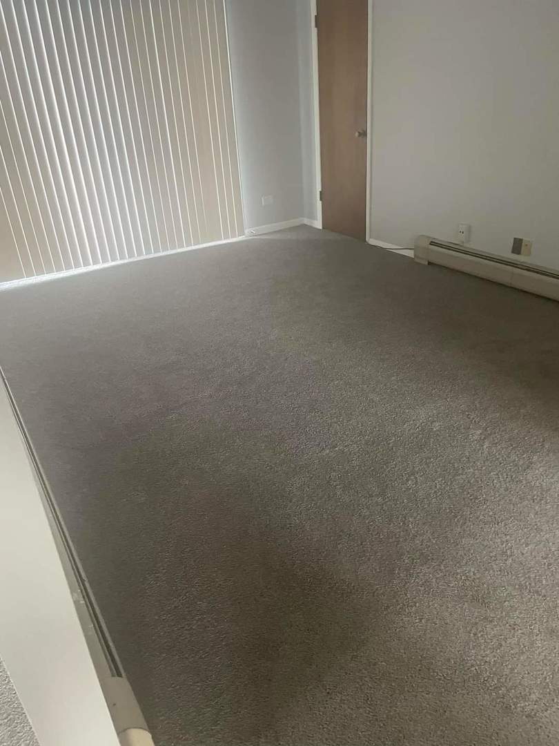 carpeted spare room featuring a baseboard radiator