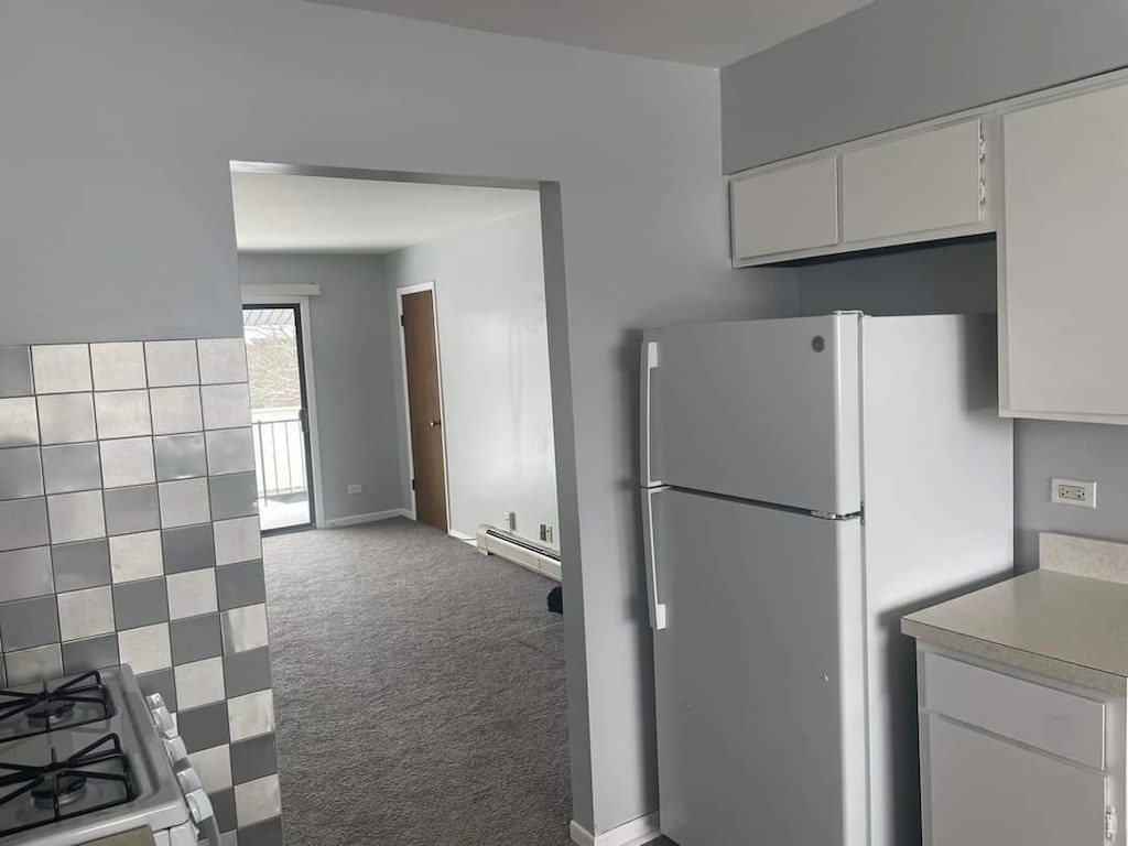 kitchen featuring white cabinets, light countertops, carpet floors, freestanding refrigerator, and a baseboard radiator