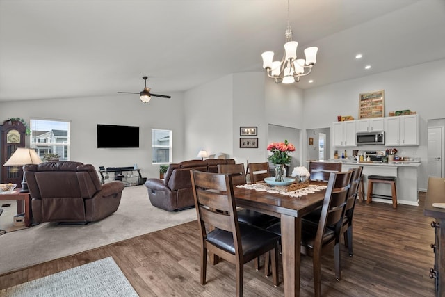 dining area with dark wood finished floors, ceiling fan with notable chandelier, high vaulted ceiling, and recessed lighting