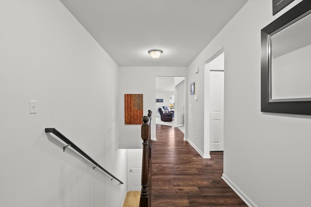 corridor featuring baseboards, wood finished floors, and an upstairs landing