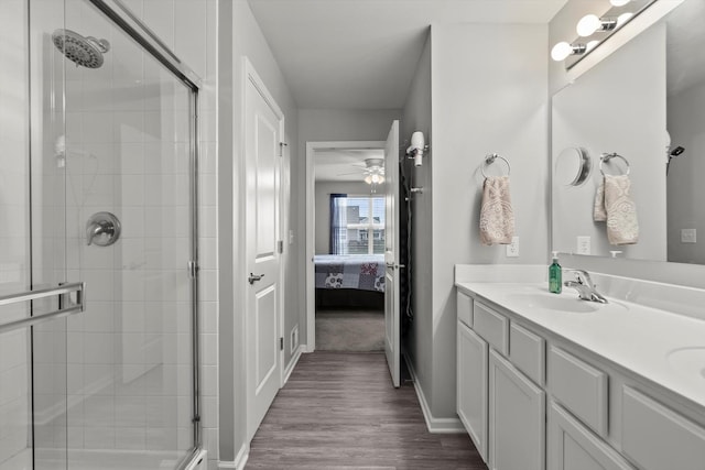 bathroom featuring double vanity, wood finished floors, tiled shower, a sink, and ensuite bath