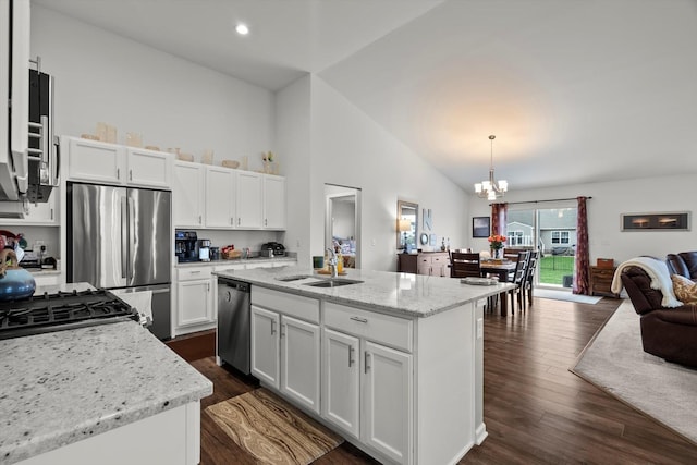 kitchen with white cabinets, appliances with stainless steel finishes, a sink, open floor plan, and an inviting chandelier