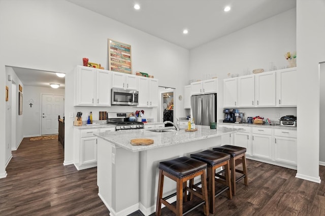 kitchen with a breakfast bar, white cabinets, a high ceiling, and appliances with stainless steel finishes