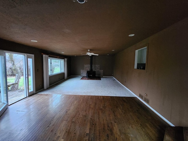 1122 Foster Ave, Lake Bluff, IL 60044 - unfurnished living room featuring ceiling fan, a wood stove, visible vents, wood finished floors, and baseboards