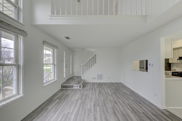 12525 S Central Park Ave, Alsip, IL 60803 - unfurnished living room with light wood-type flooring, a high ceiling, visible vents, and stairway