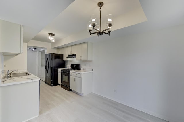 12525 S Central Park Ave, Alsip, IL 60803 - kitchen with under cabinet range hood, a chandelier, a sink, light wood-style flooring, and black appliances