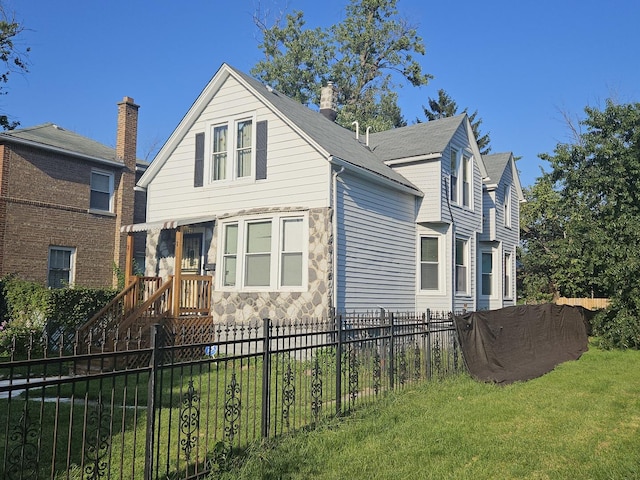view of front of home featuring stone siding, fence private yard, and a front yard