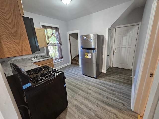 kitchen featuring a sink, freestanding refrigerator, wood finished floors, light brown cabinetry, and gas stove