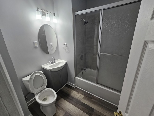 full bath featuring toilet, vanity, combined bath / shower with glass door, and wood finished floors