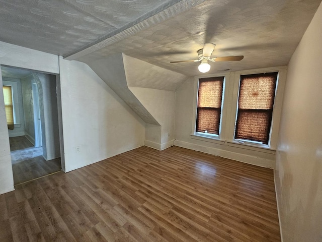 bonus room featuring a textured ceiling, vaulted ceiling, wood finished floors, and a ceiling fan