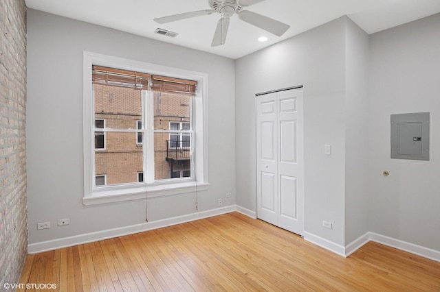 spare room featuring electric panel, visible vents, plenty of natural light, and light wood-style flooring