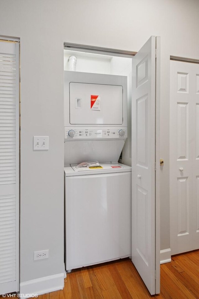 laundry room with light wood finished floors, stacked washing maching and dryer, and laundry area