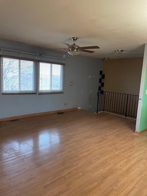 spare room with a ceiling fan, light wood-style flooring, baseboards, and visible vents