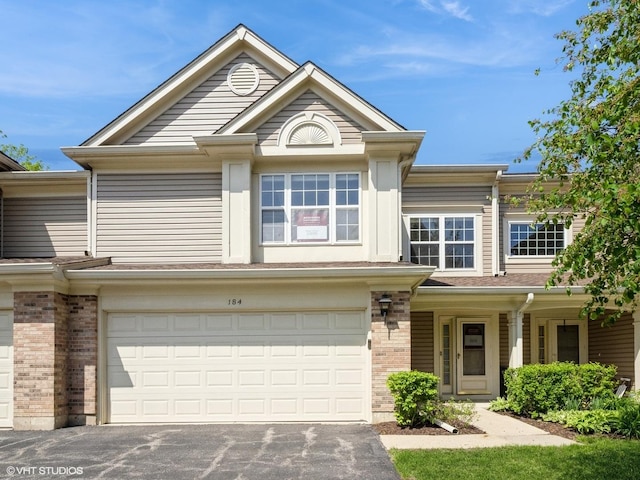 view of front of property with an attached garage, asphalt driveway, and brick siding