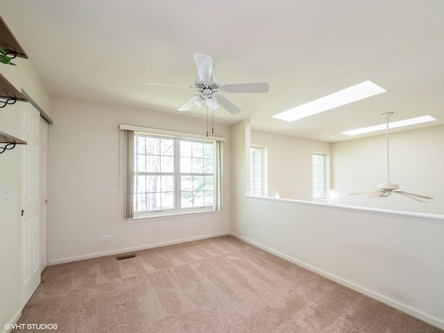 unfurnished room with ceiling fan, light colored carpet, baseboards, and healthy amount of natural light
