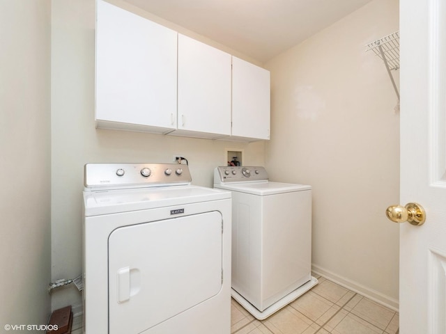 laundry area with washing machine and clothes dryer, cabinet space, light tile patterned floors, and baseboards