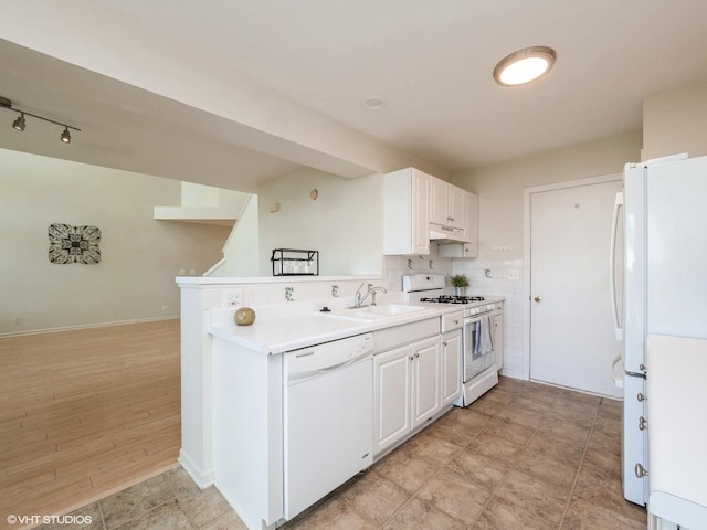 kitchen with white appliances, a sink, under cabinet range hood, light countertops, and white cabinetry