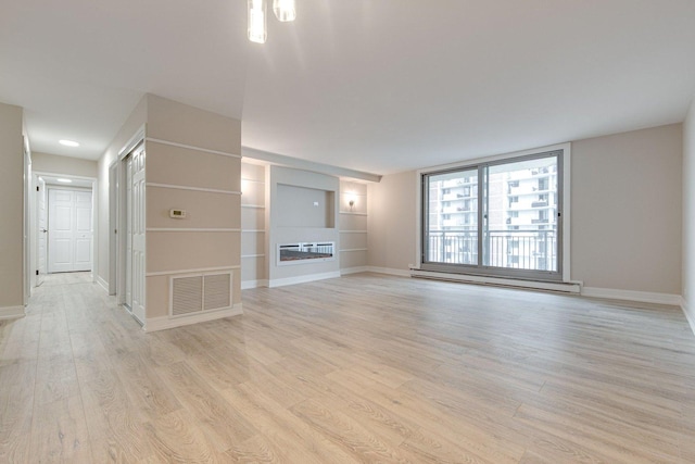 unfurnished living room featuring a baseboard heating unit, baseboards, light wood finished floors, and visible vents