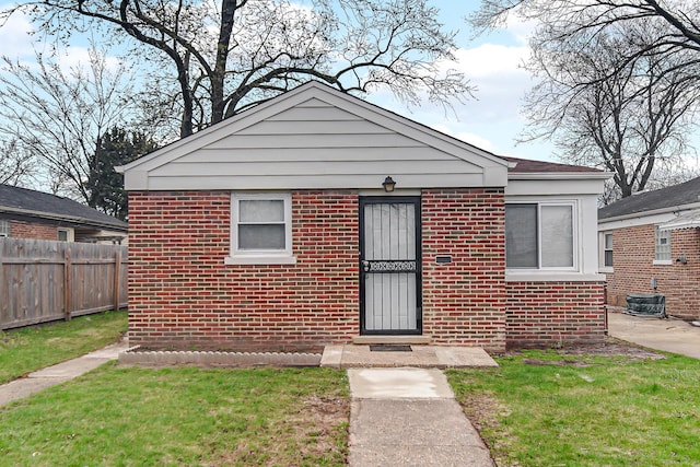 bungalow-style home with cooling unit, fence, and brick siding