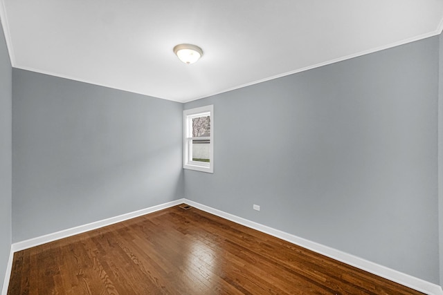 unfurnished room with crown molding, baseboards, and dark wood finished floors