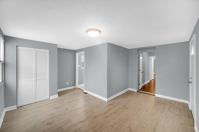 unfurnished bedroom featuring wood finished floors, baseboards, and a closet