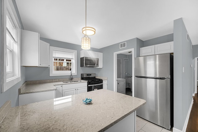 kitchen featuring white cabinetry, visible vents, a sink, hanging light fixtures, and stainless steel appliances