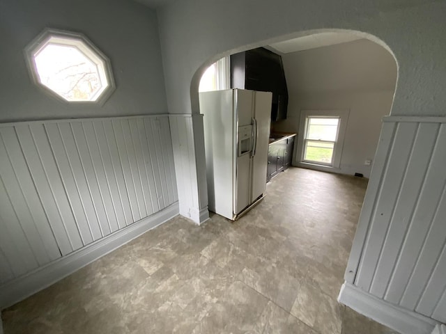 409 Chandler St, Danville, IL 61832 - interior space with white refrigerator with ice dispenser, a wainscoted wall, concrete floors, and arched walkways