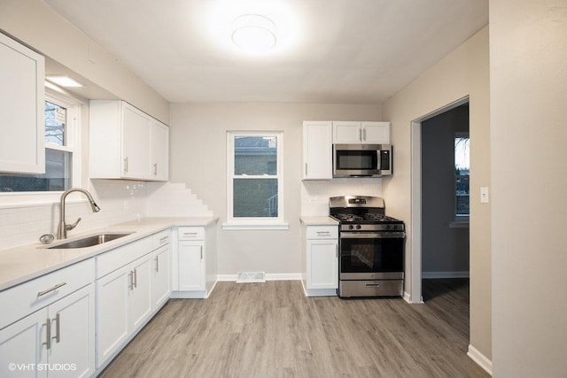 270 W 10th St, Chicago Heights, IL 60411 - kitchen featuring decorative backsplash, white cabinets, light countertops, stainless steel appliances, and a sink