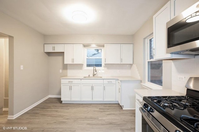 270 W 10th St, Chicago Heights, IL 60411 - kitchen with light countertops, white cabinets, a sink, and stainless steel appliances