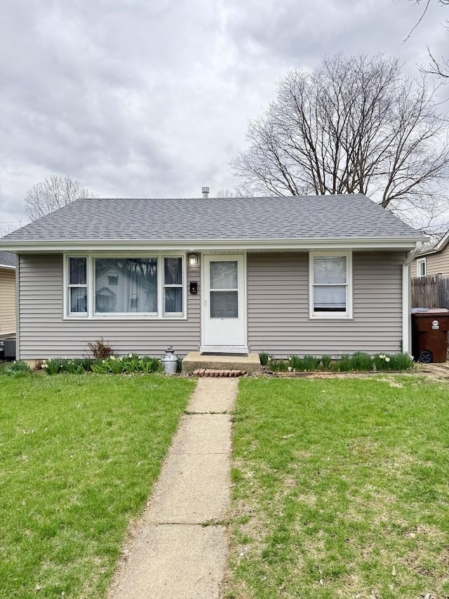 ranch-style house featuring roof with shingles and a front lawn