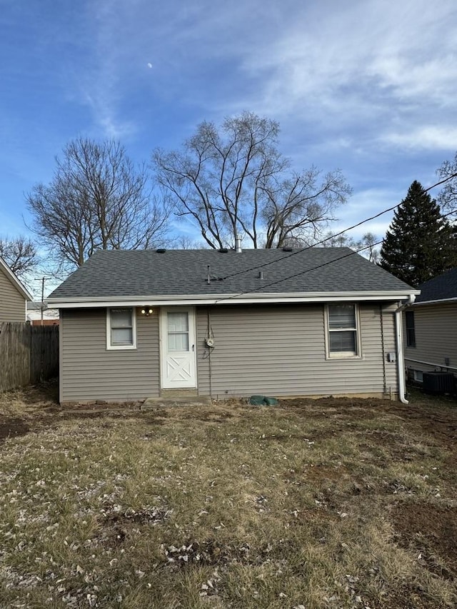 back of property with roof with shingles, central air condition unit, and fence