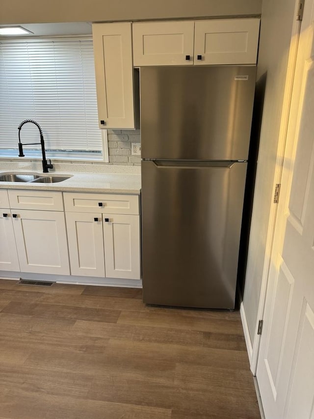 kitchen with visible vents, a sink, freestanding refrigerator, dark wood-style floors, and white cabinetry