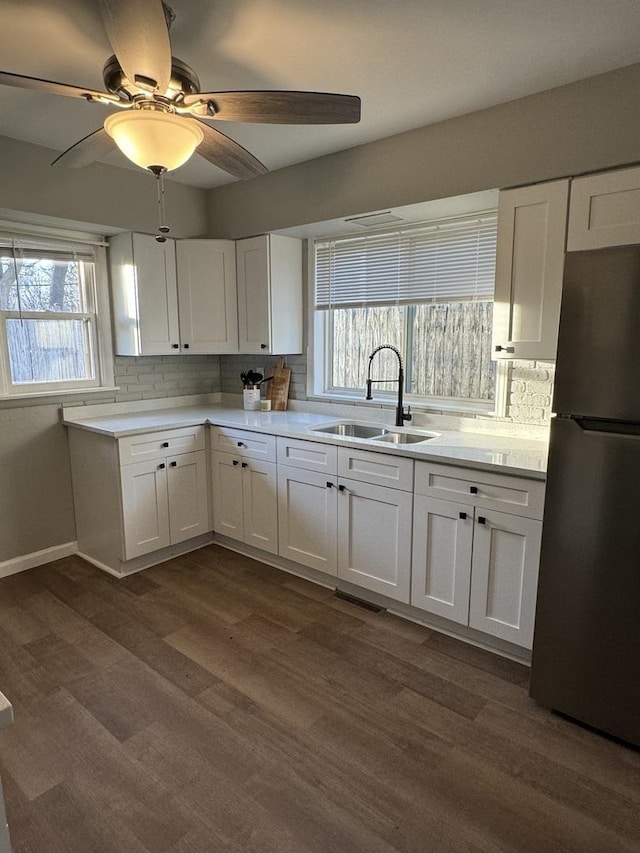 kitchen featuring freestanding refrigerator, a sink, and white cabinets