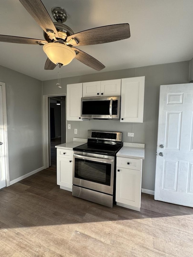 kitchen with stainless steel appliances, dark wood-type flooring, white cabinets, and light countertops