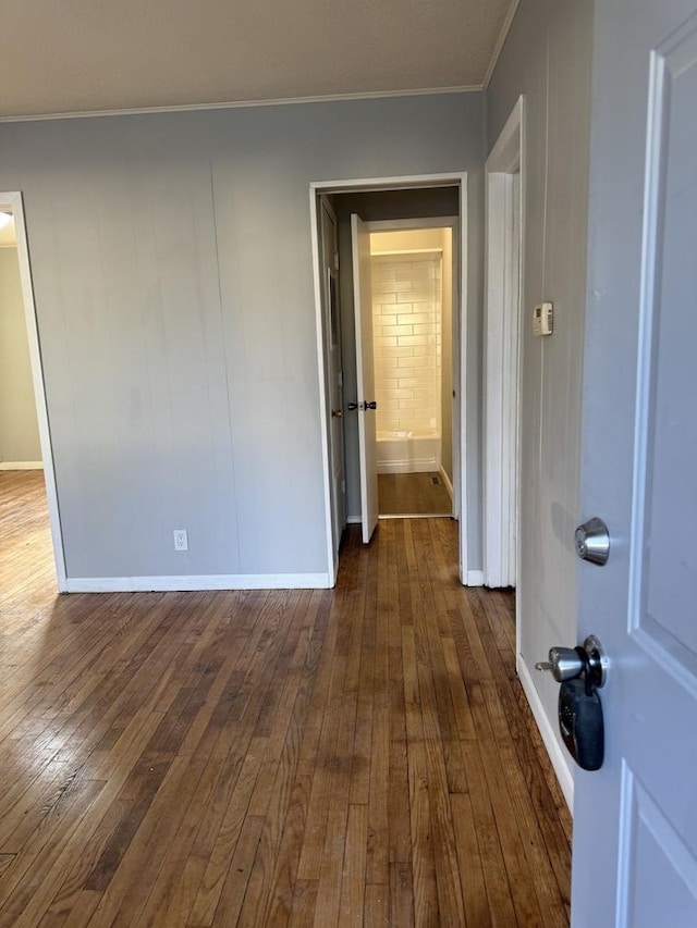 unfurnished room featuring dark wood-type flooring, baseboards, and crown molding