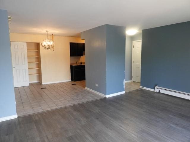 13715 S Stewart Ave Unit 2E, Riverdale, IL 60827 - empty room with a chandelier, dark wood-style floors, baseboards, and a baseboard heating unit