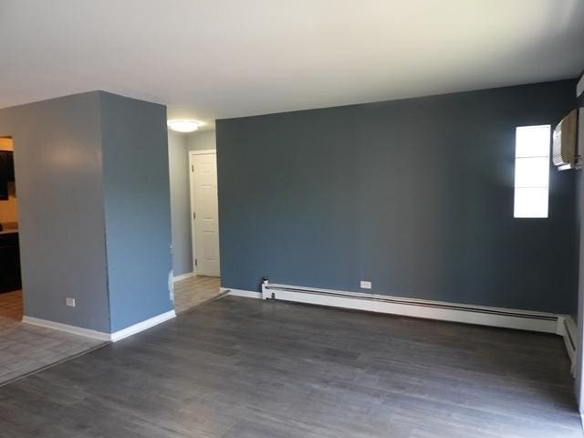 13715 S Stewart Ave Unit 2E, Riverdale, IL 60827 - empty room featuring a baseboard heating unit, wood finished floors, and baseboards