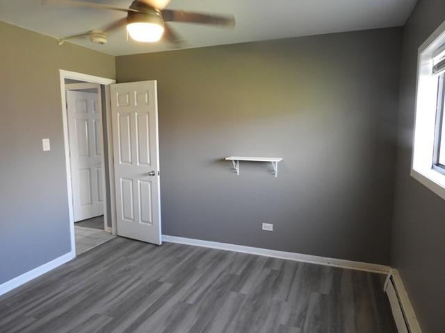 13715 S Stewart Ave Unit 2E, Riverdale, IL 60827 - empty room featuring baseboard heating, ceiling fan, wood finished floors, and a smoke detector